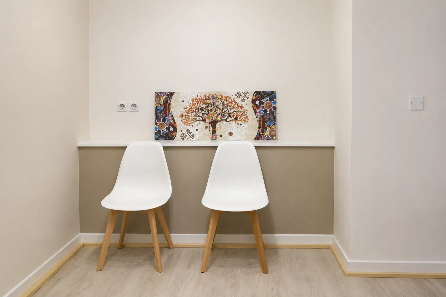 Espace d'accueil du cabinet avec deux chaises blanches et un tableau coloré